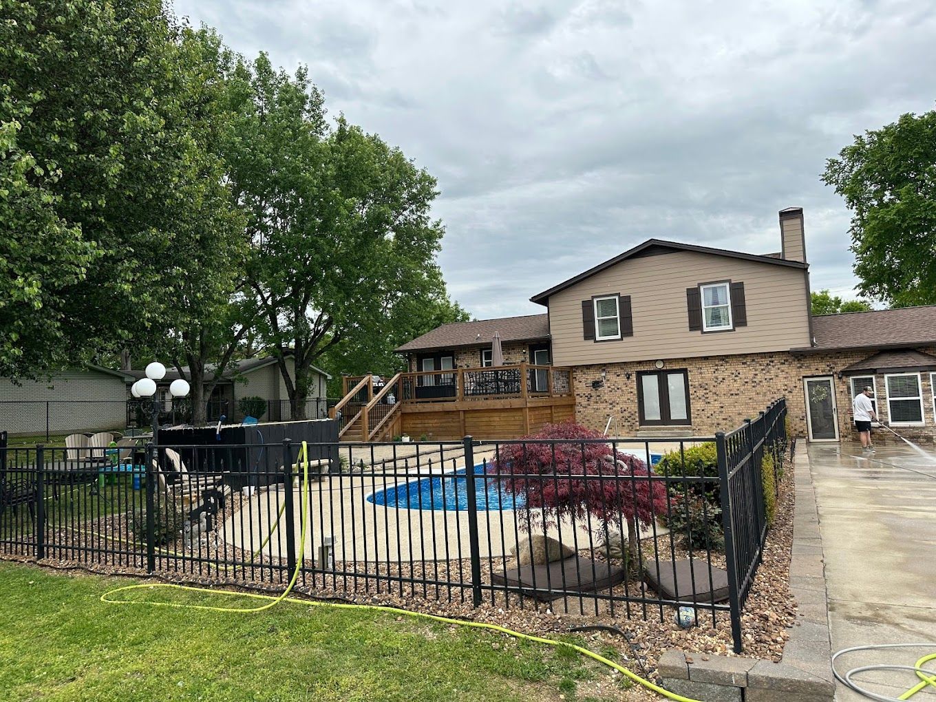 man pressure washing poolside