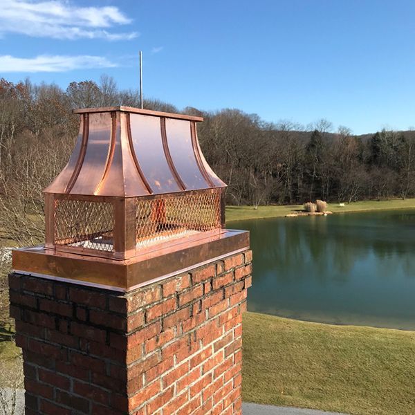 Copper chimney cap on brick chimney, overlooking a lake.