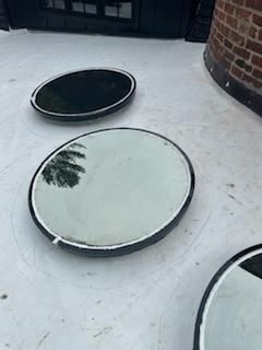 Circular skylights on a white rooftop reflect the sky.