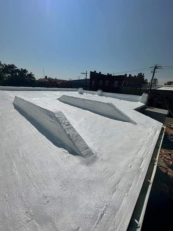 White painted flat roof with angled structures, against a clear blue sky.