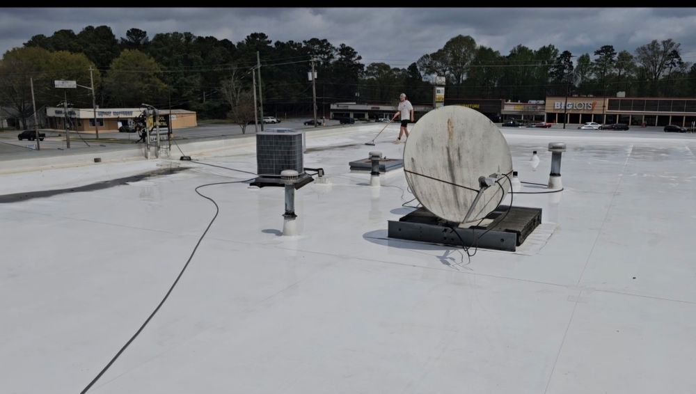 White rooftop with equipment, a person, and a street in the background.