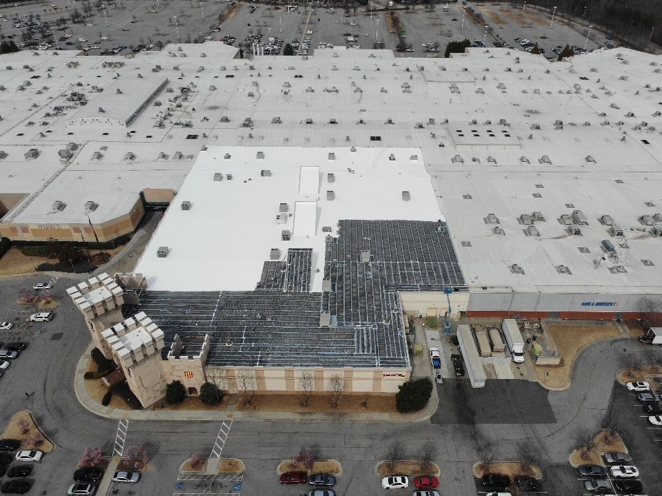 Overhead view of a large building complex with a castle-like structure in the foreground and a large parking area.