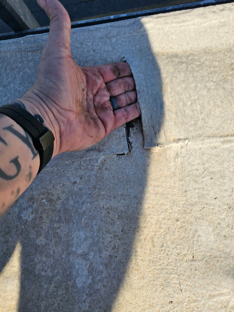 Hand placed in a square cut in a concrete surface. The hand has a black watch and a tattoo.