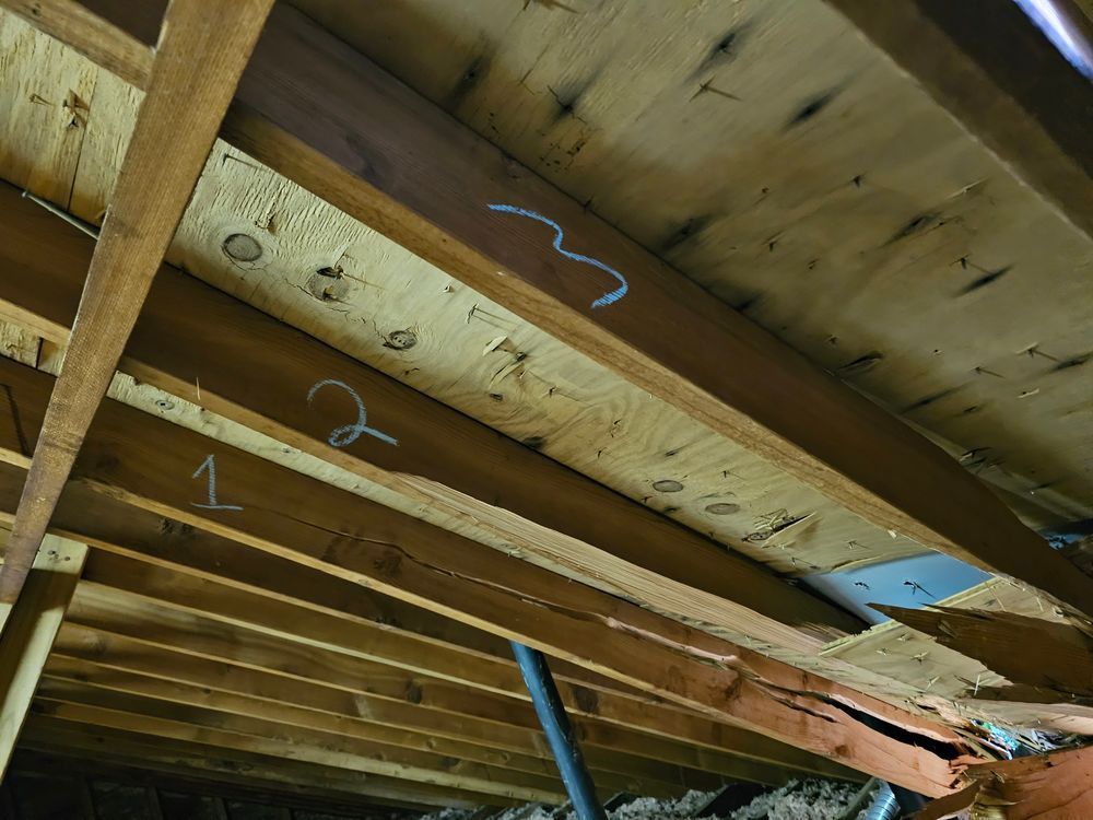 Interior view of attic ceiling with numbered wooden beams.