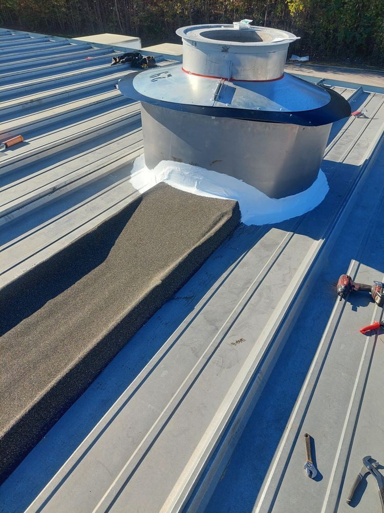 Metal roof with an exhaust fan installation; white sealant applied.