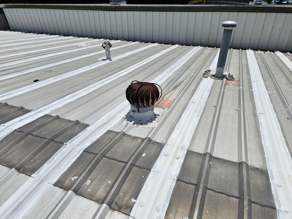 Metal industrial roof with vents and stains.