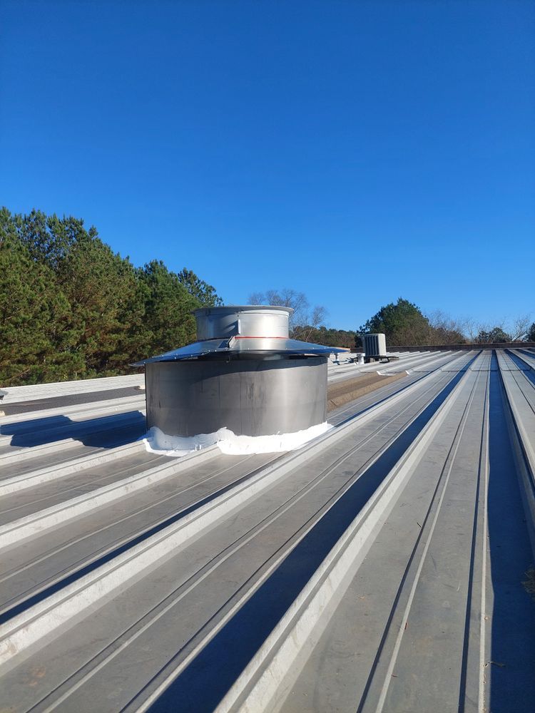 Metal roof with a cylindrical vent on a sunny day.