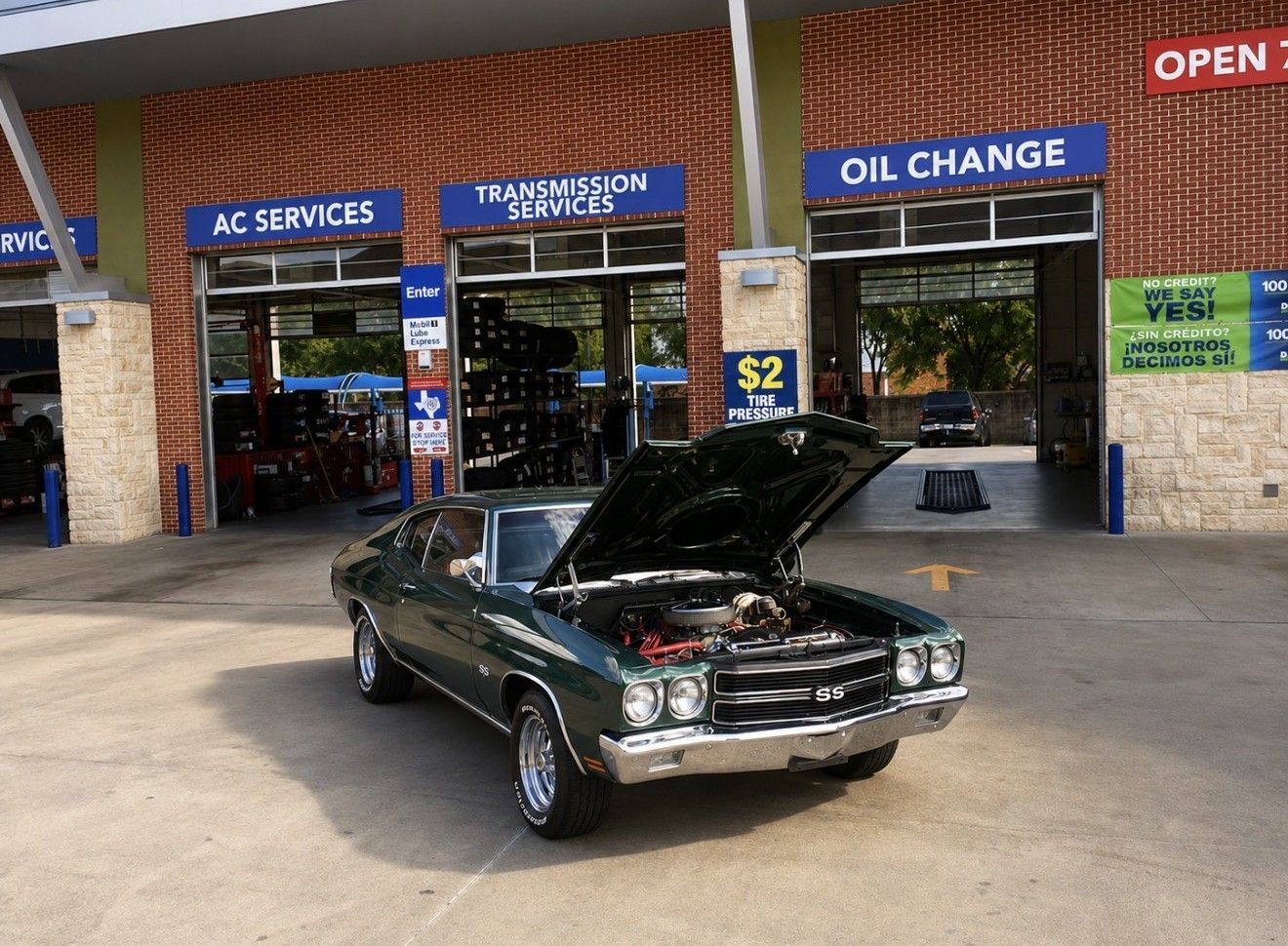 Classic black car parked outside an auto service shop with blue signs and an open garage.