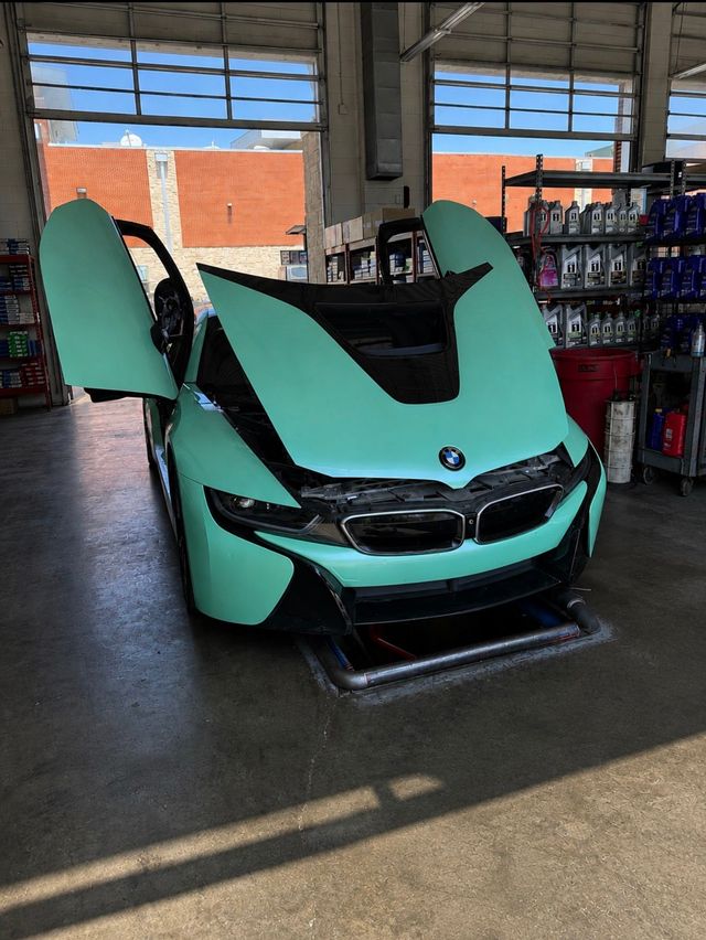 Mint green sports car with doors open, displayed indoors in a showroom or garage.