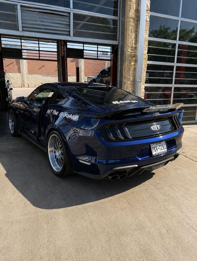 Dark blue sports car parked outside a garage with its driver door open