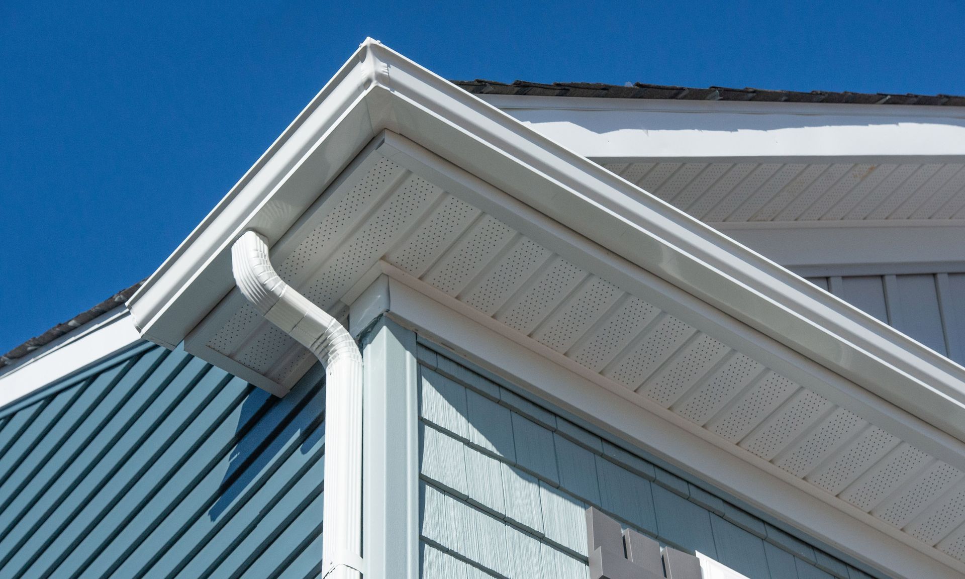 a house with a white gutter and a blue siding.