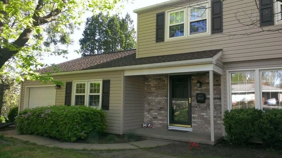 the front of a house with a porch and a garage.