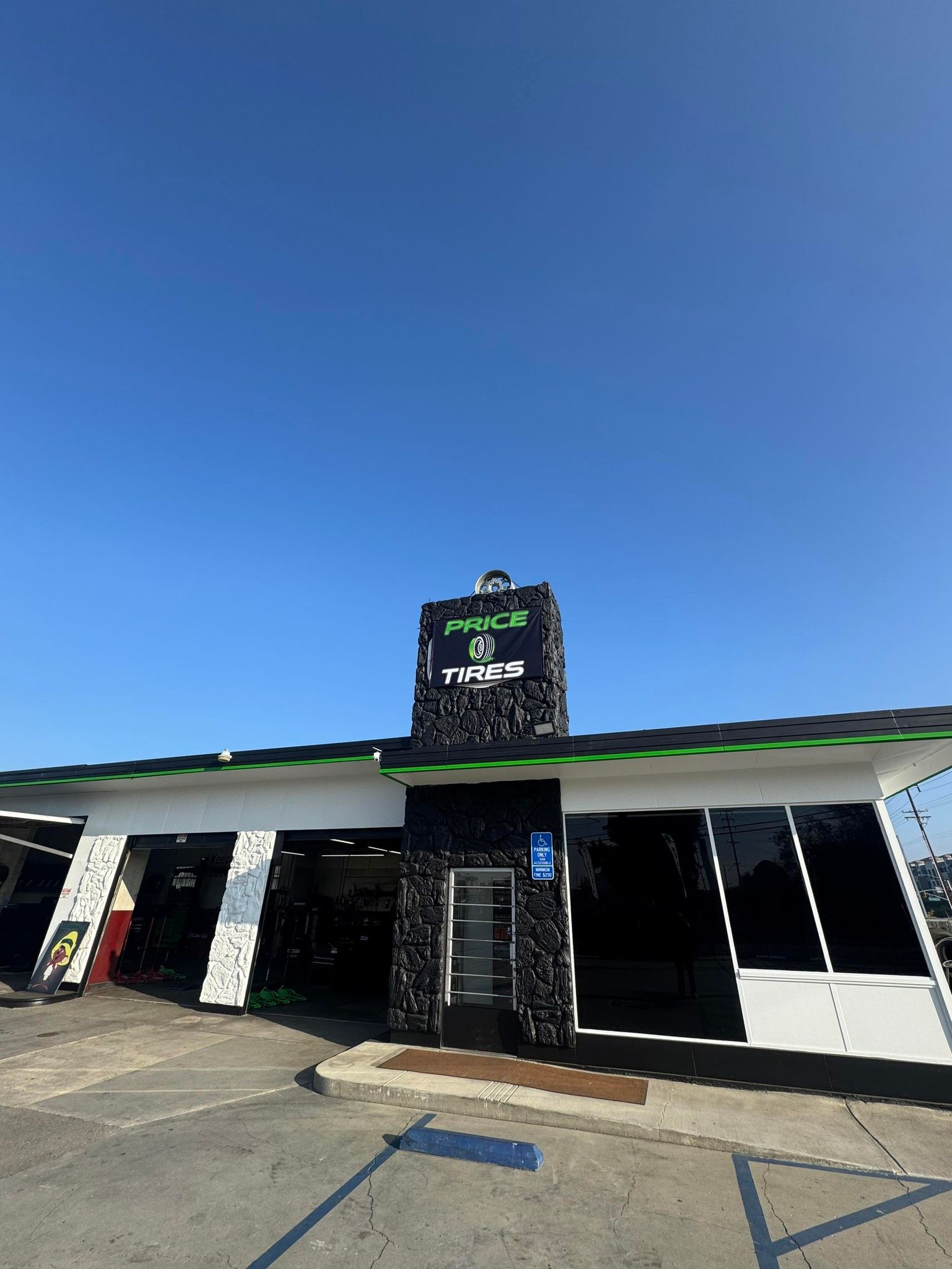 A single-story commercial building with black stone accents, white trim, and dark windows under a clear blue sky.