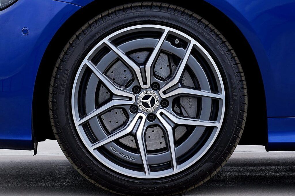 A close-up of a blue Mercedes-Benz car's dark metallic alloy wheel with a multi-spoke design and a visible brake disc.