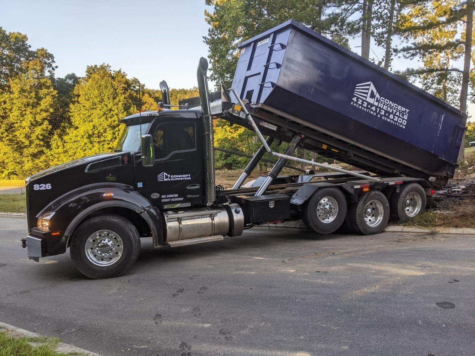 A dumpster truck is parked on the side of the road.