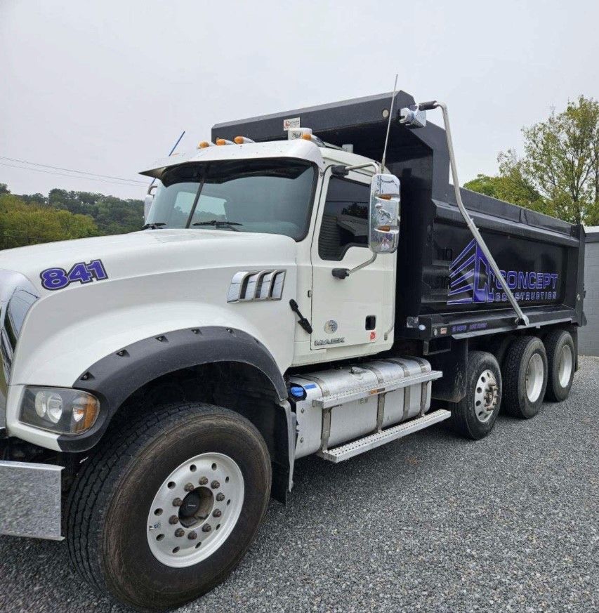 A white dump truck is parked in a gravel lot.