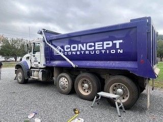 A blue dump truck is parked in a gravel lot.