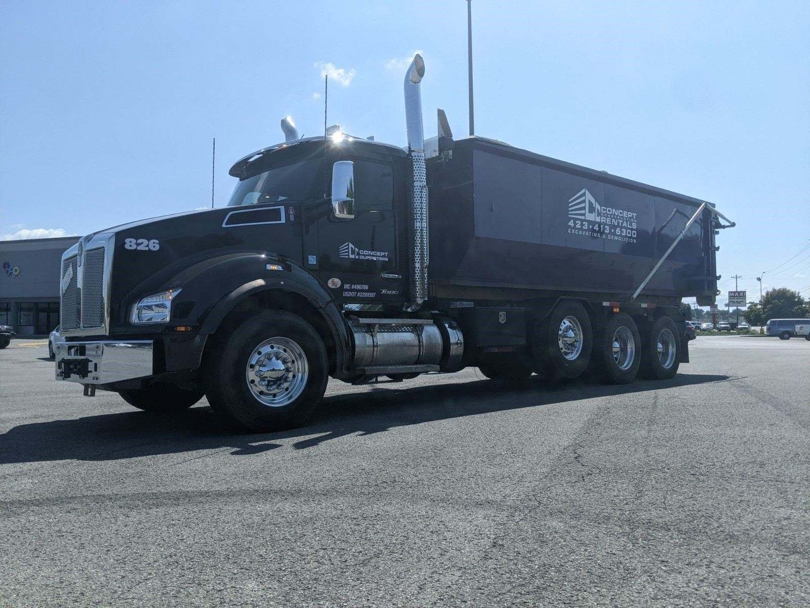 A black dump truck is parked on the side of the road.