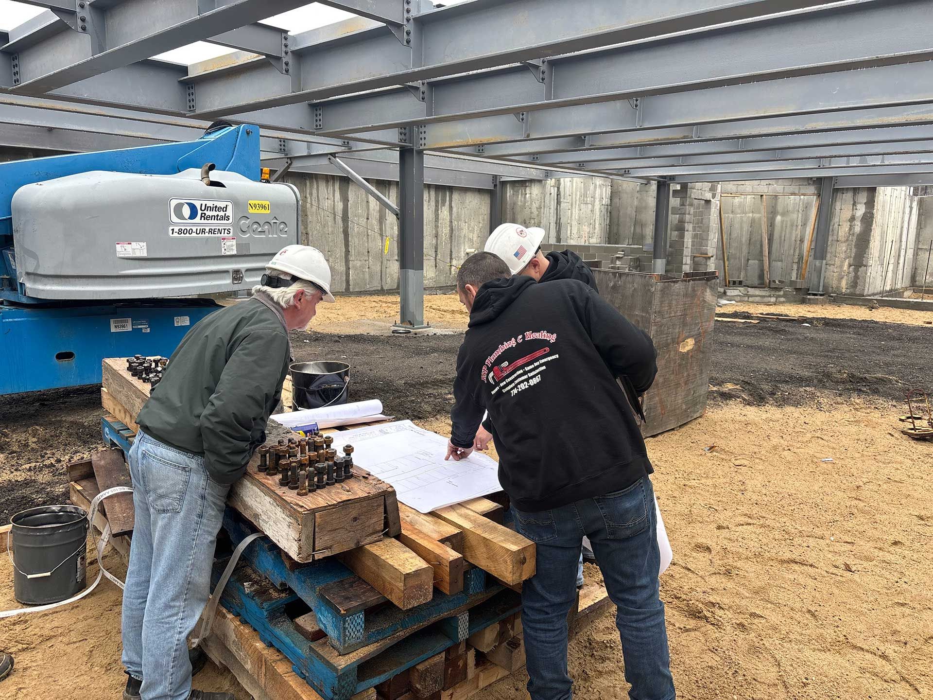 a group of men are looking at a blueprint on a construction site