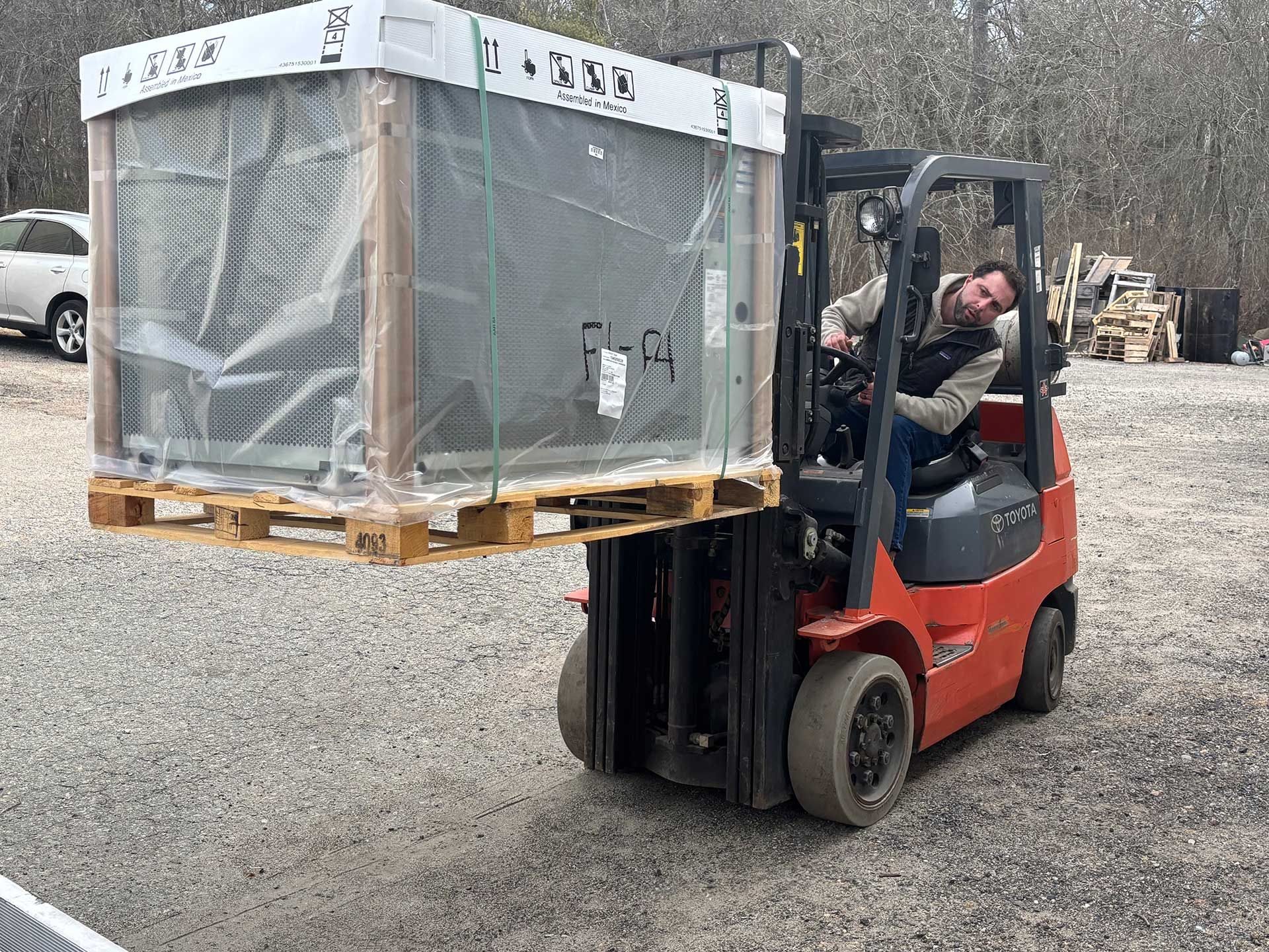 a man is driving a forklift carrying a large box on a pallet