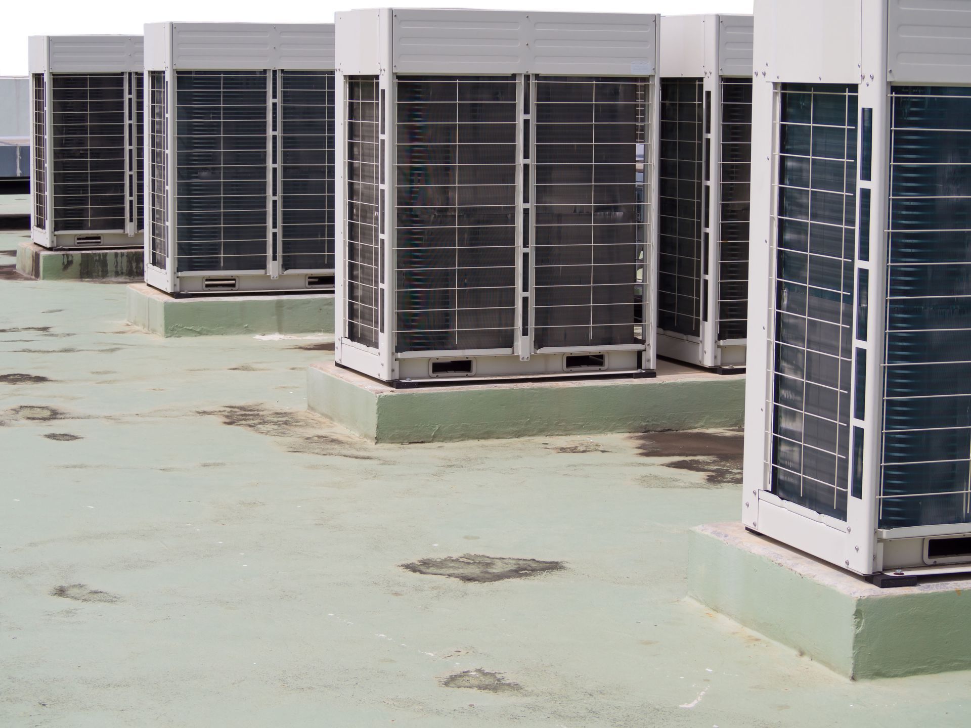A row of commercial HVAC units are sitting on top of a green roof