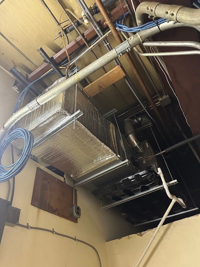 a ceiling with a lot of pipes and wires hanging from it