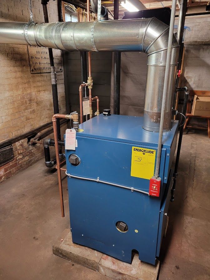 a blue boiler is sitting in a basement next to a brick wall
