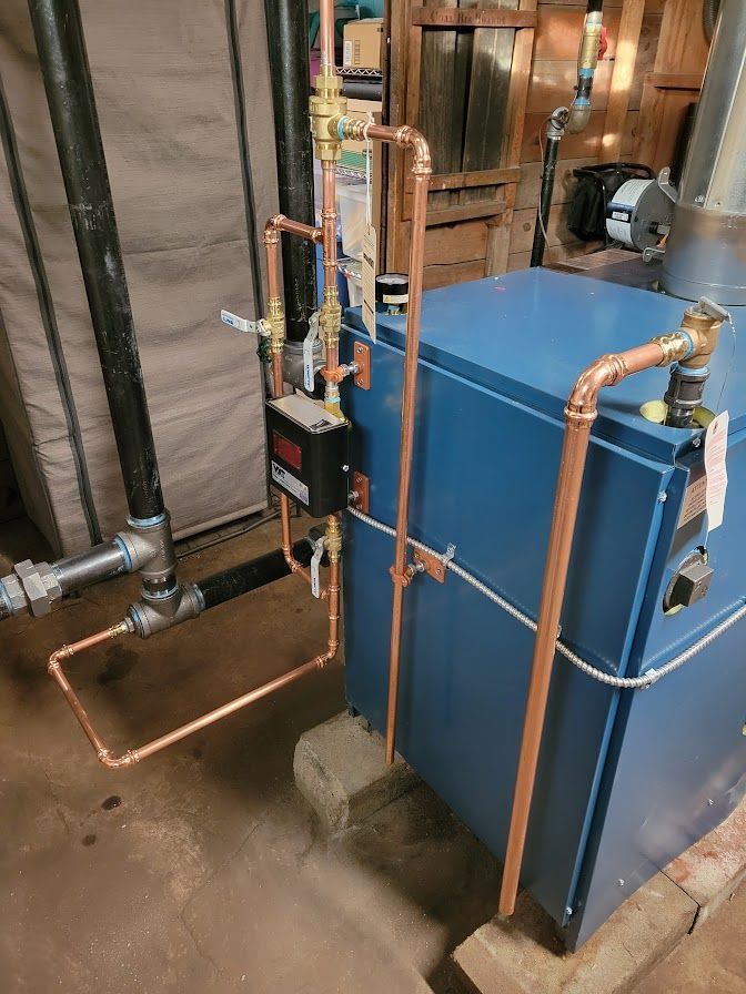 a blue boiler with copper pipes attached to it is sitting in a basement