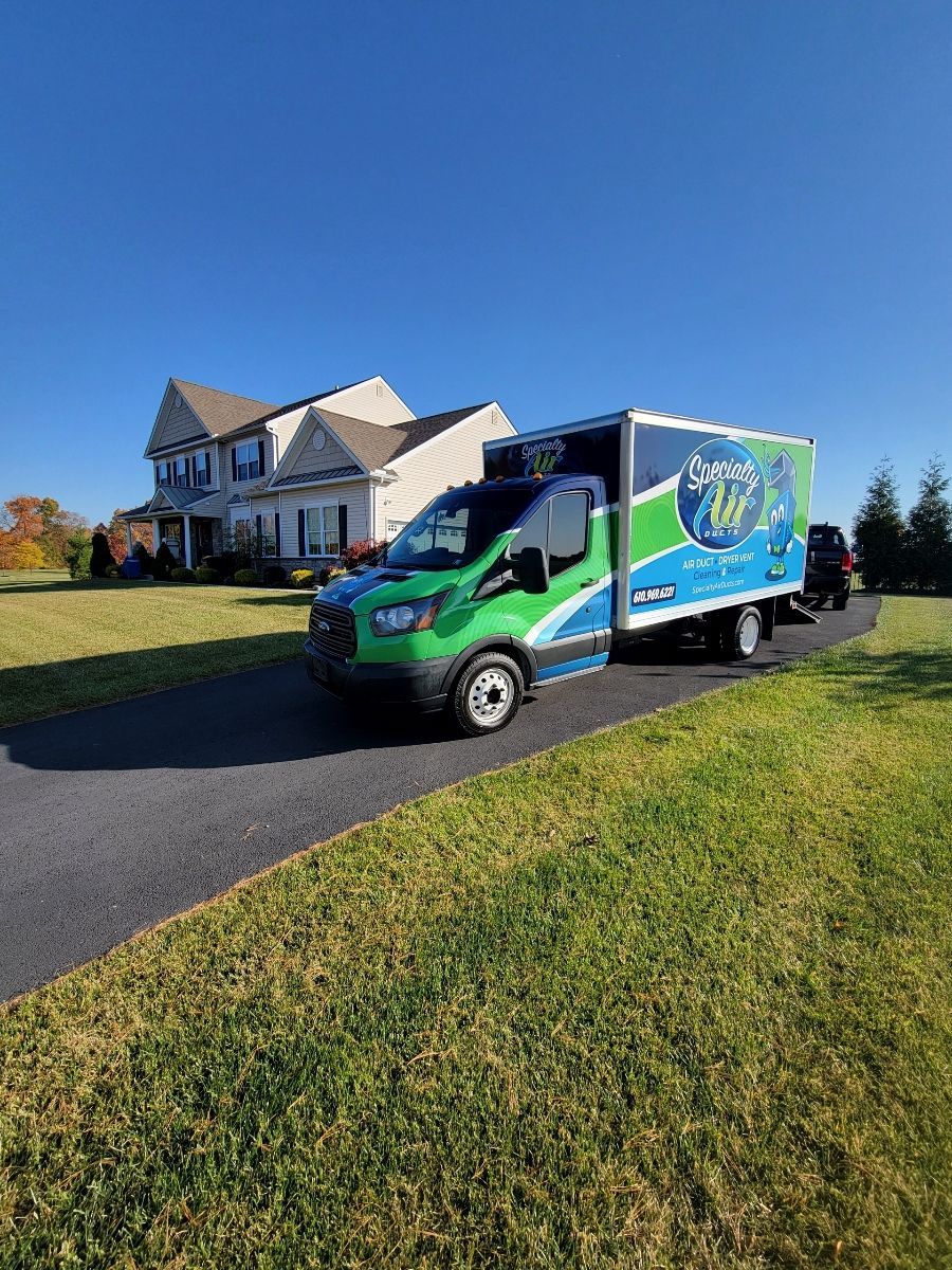 A green and blue moving truck is parked in front of a home.