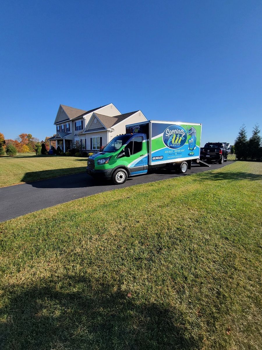 A green and blue van is parked in front of a house.