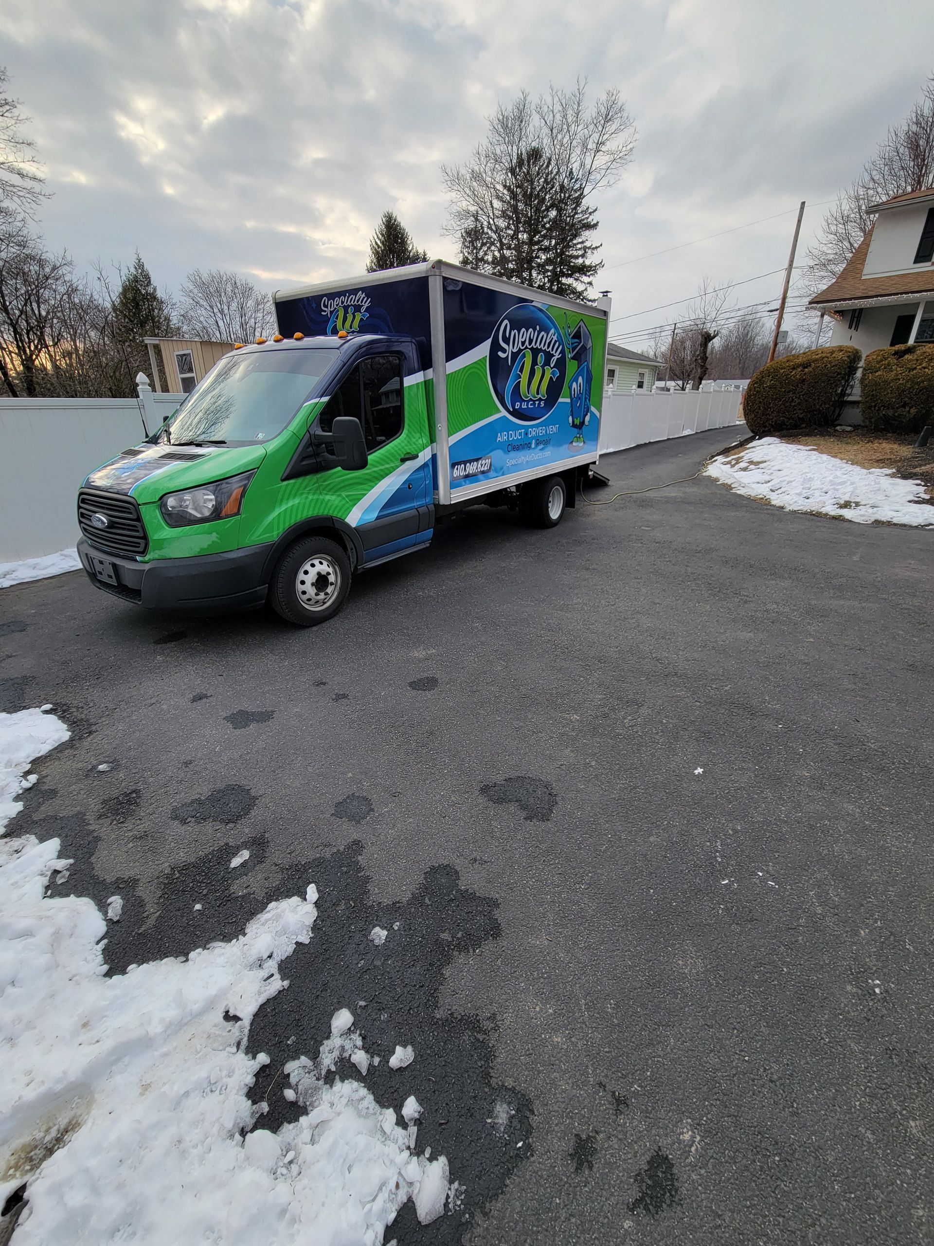 A green and blue van is driving down a snowy road.
