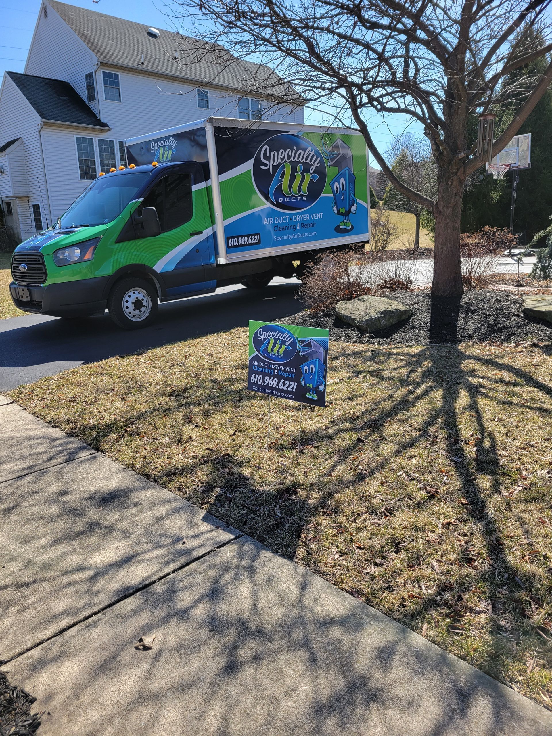 A green and blue van is parked in front of a house.