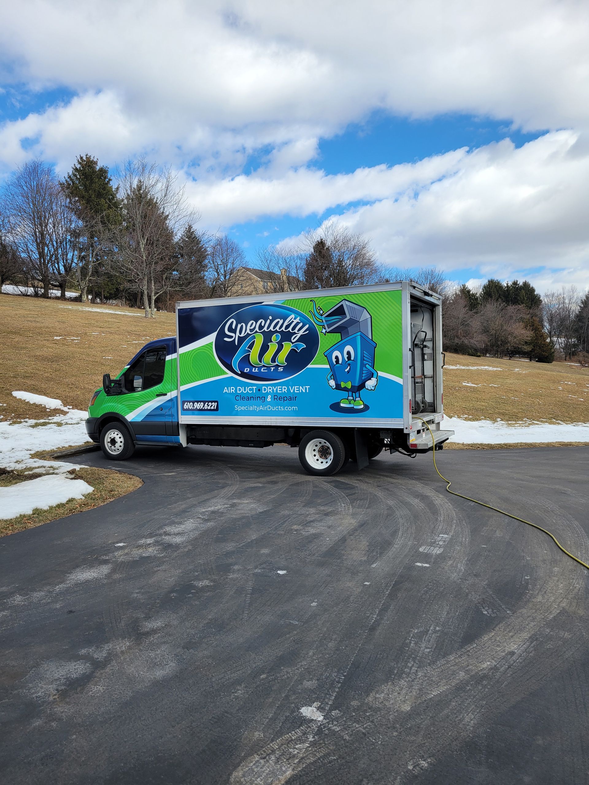 A green and blue truck is parked on the side of a road.