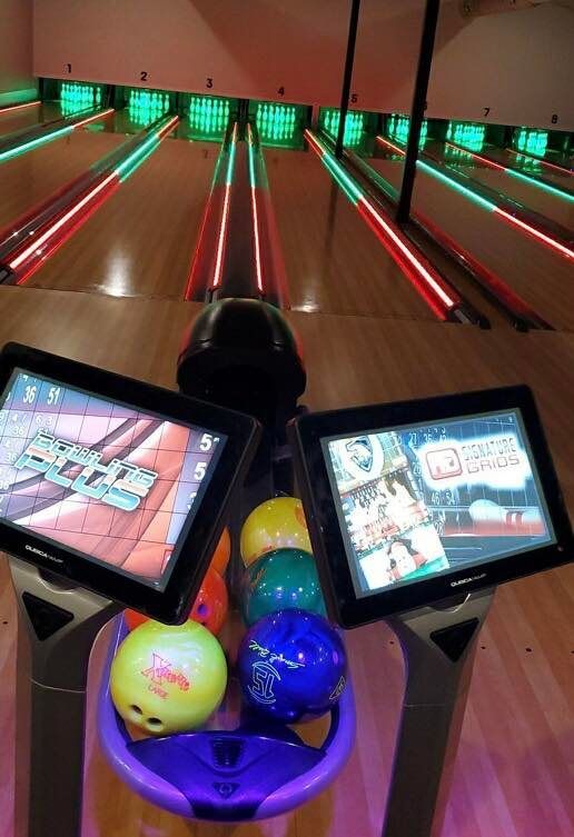 A bowling alley with two monitors and bowling balls