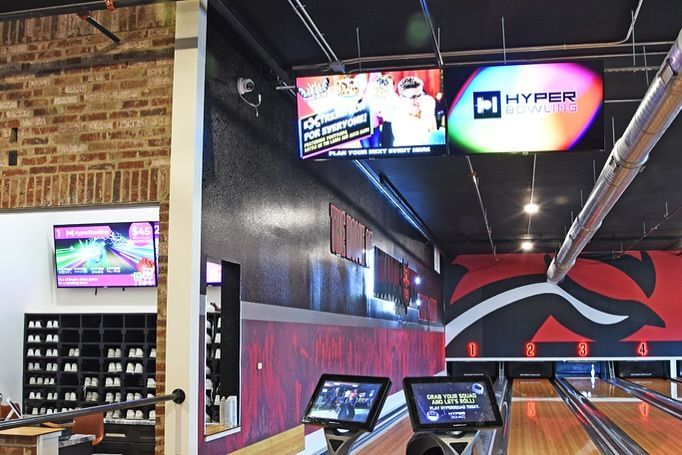 A bowling alley with two televisions hanging from the ceiling.