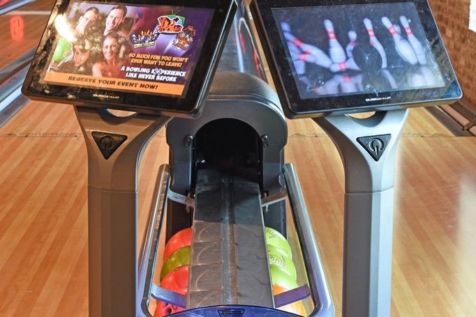 A bowling alley with two screens and a bowling ball