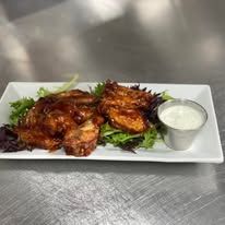 A white plate topped with chicken wings and a side of ranch dressing.