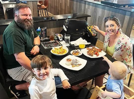 A family is sitting at a table with plates of food.