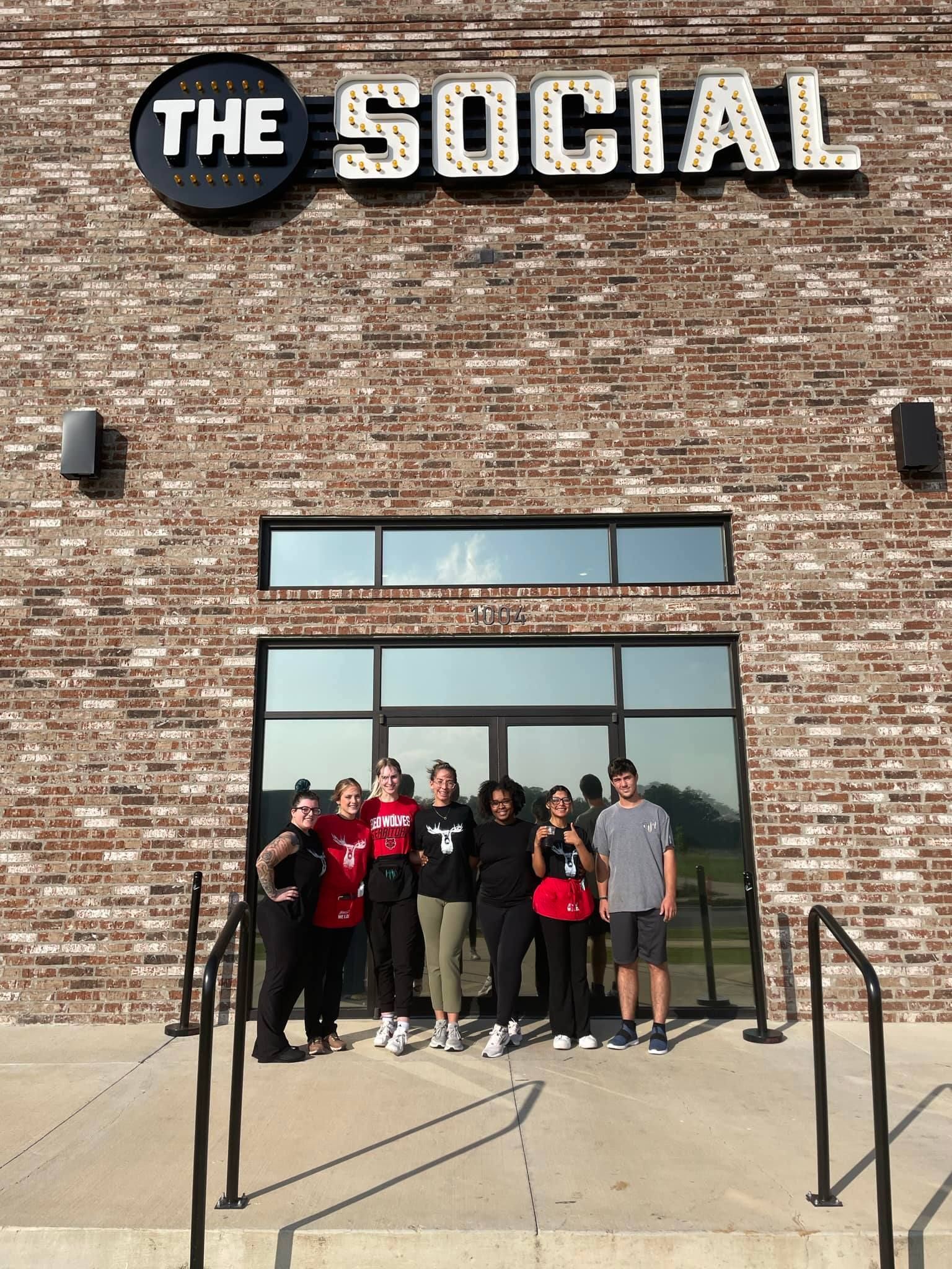 A group of people standing in front of a building that says the social