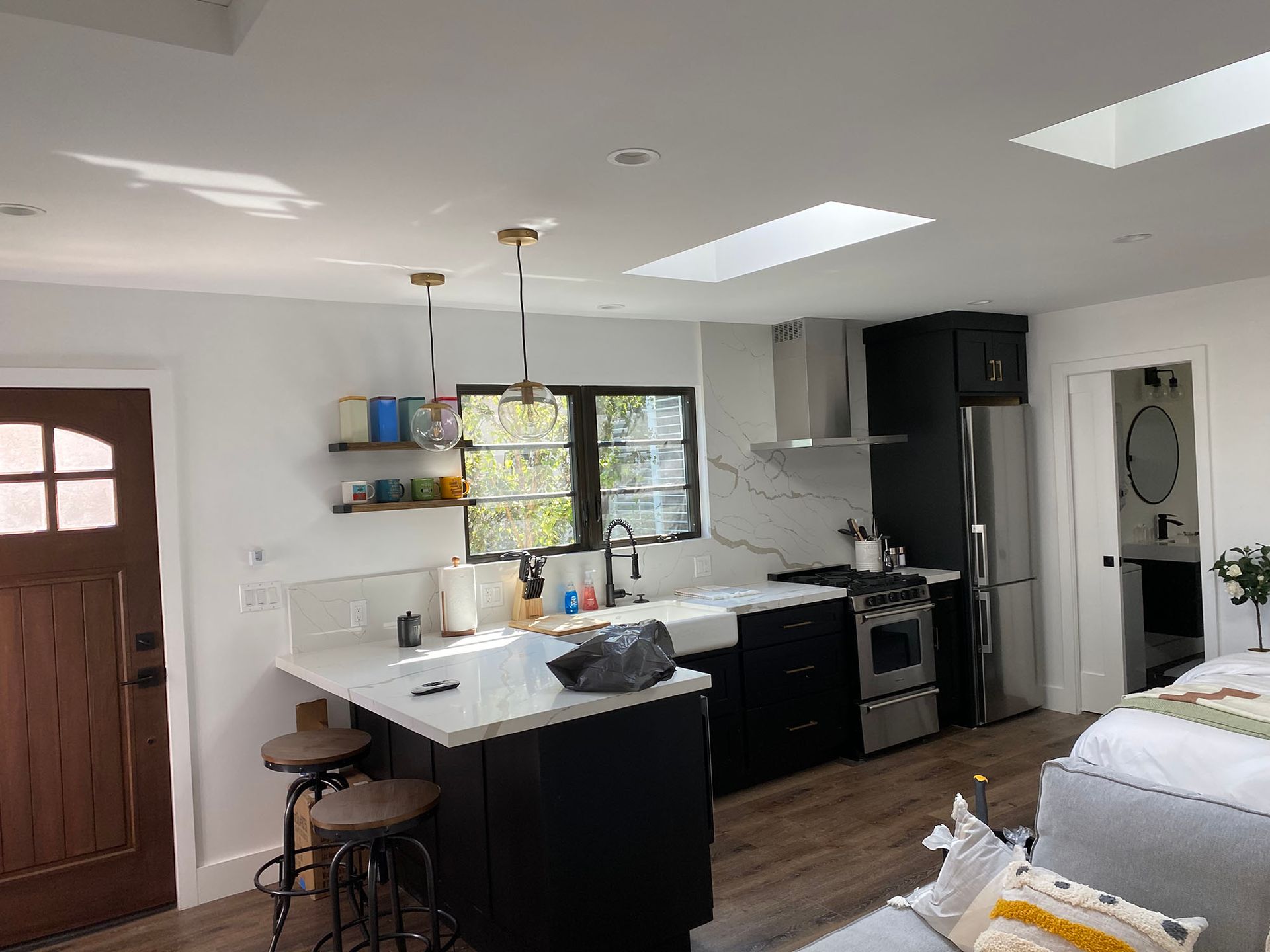 A kitchen with black cabinets , stainless steel appliances , and a skylight.