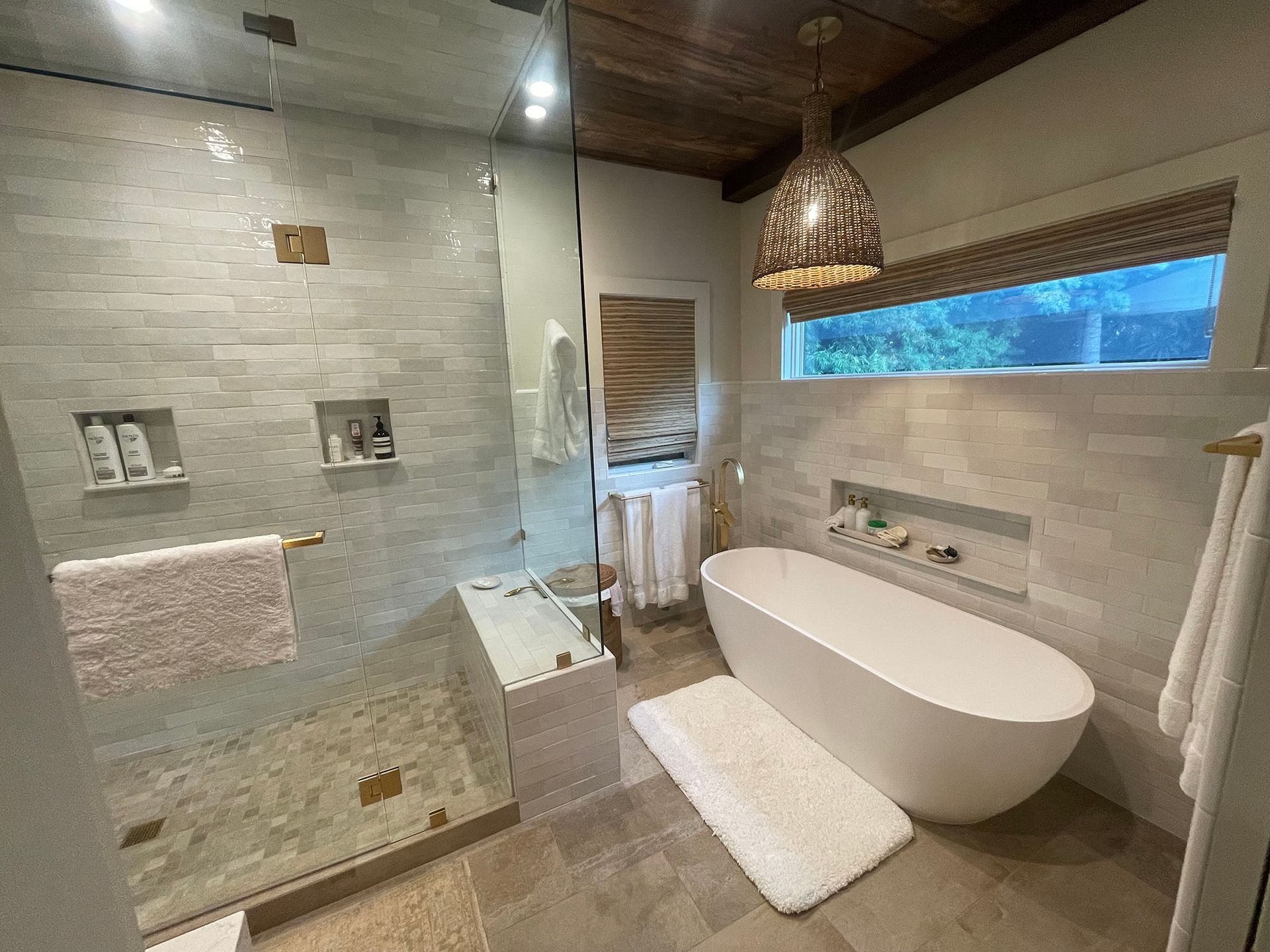 A bathroom with a tub , shower , and window.