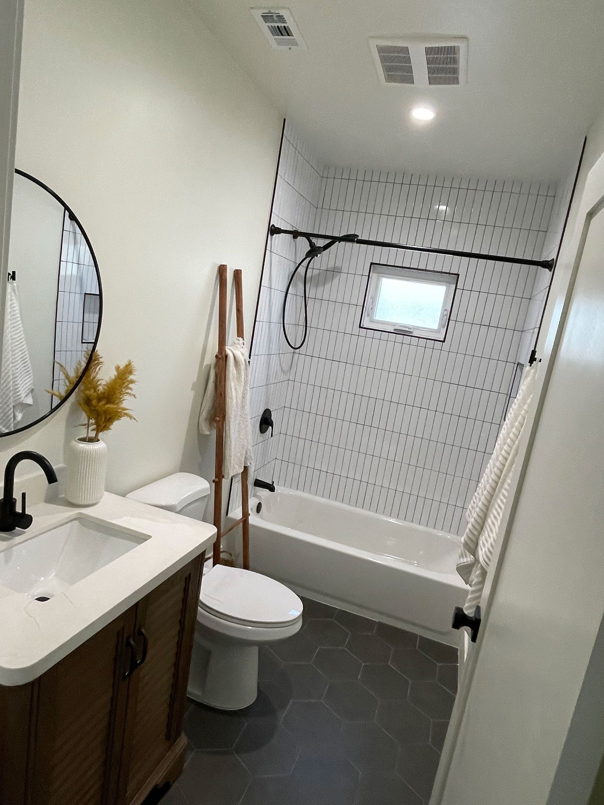A white bathroom with a toilet, sink, tub and mirror