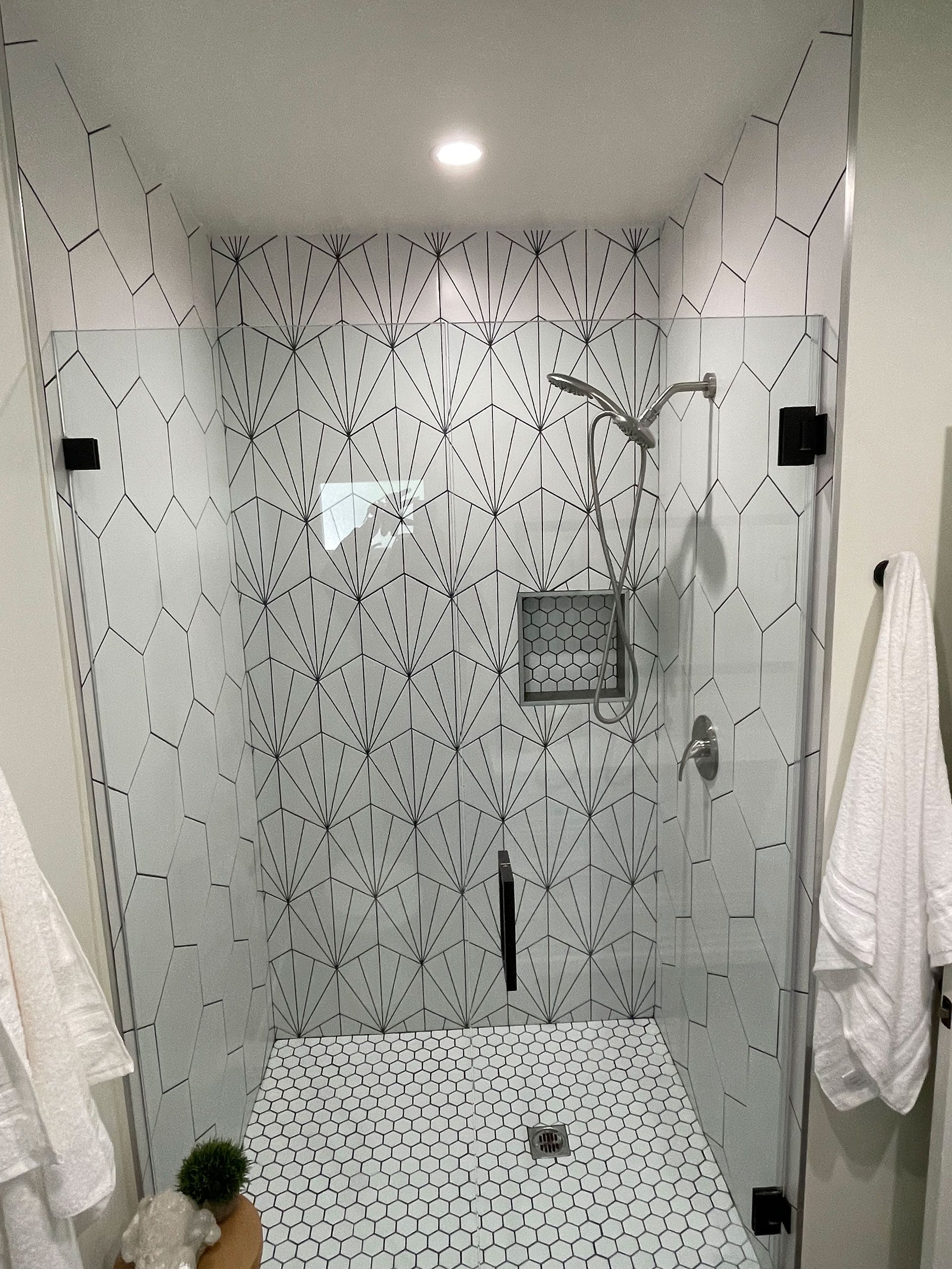 A bathroom with a walk in shower with a glass door