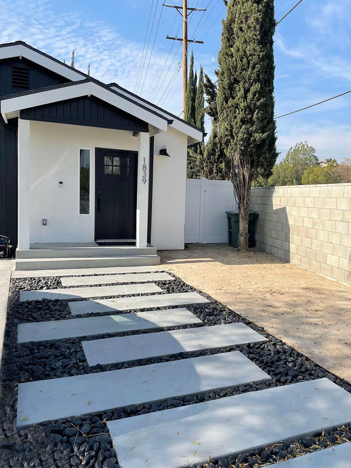 A white house with a black door and a walkway in front of it