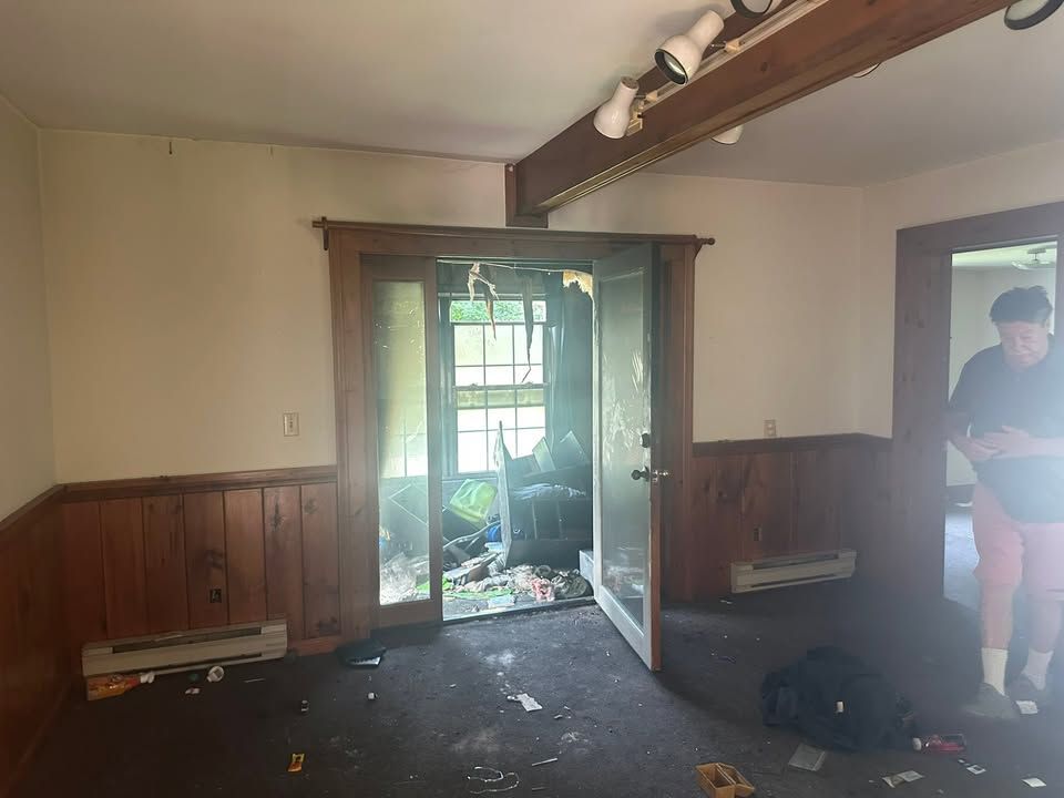 Dim room with open French doors, dark floor, wood paneling, and a person standing at right.