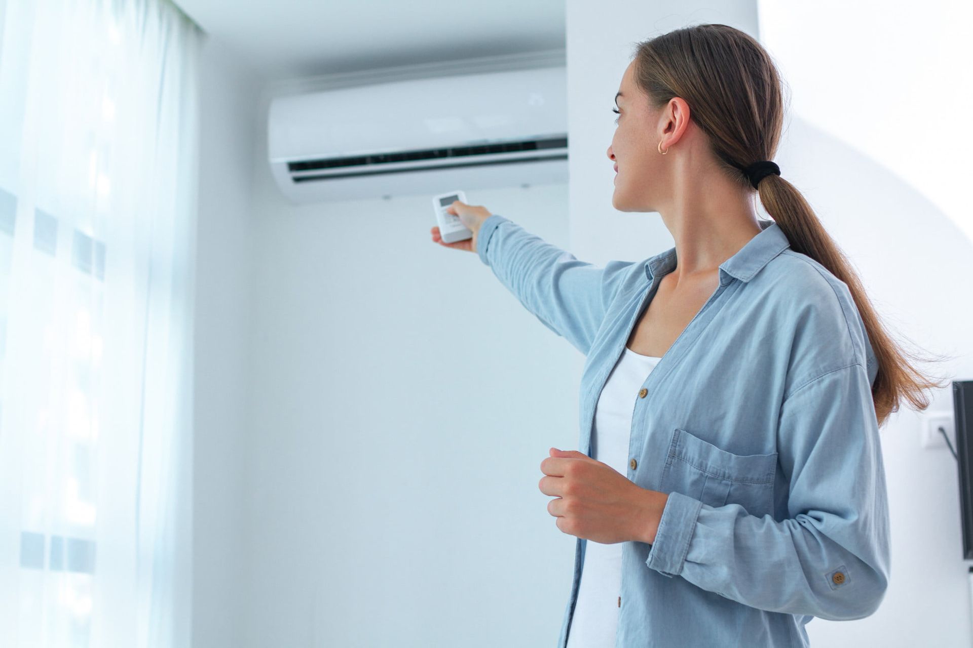 young woman adjusting clean and maintenanced air conditioner preventing HVAC water damage