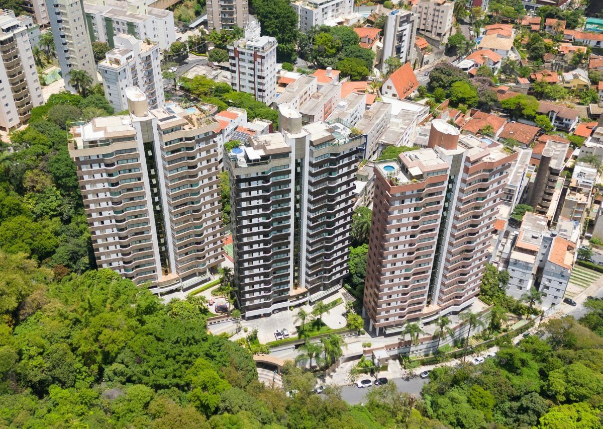 Aerial view of tall apartment towers beside a green park in a dense urban neighborhood.