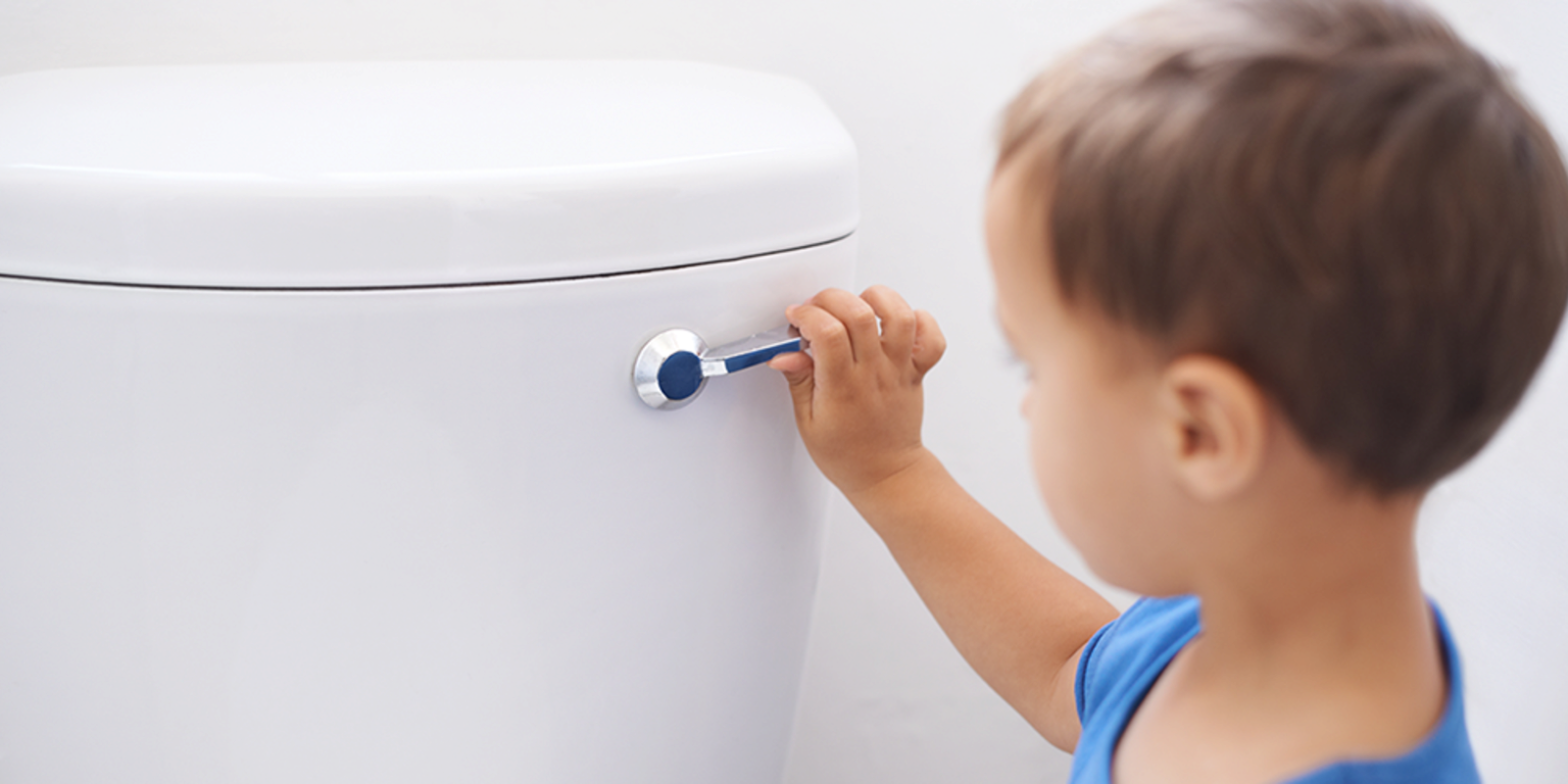 Child reaching to turn a white appliance knob