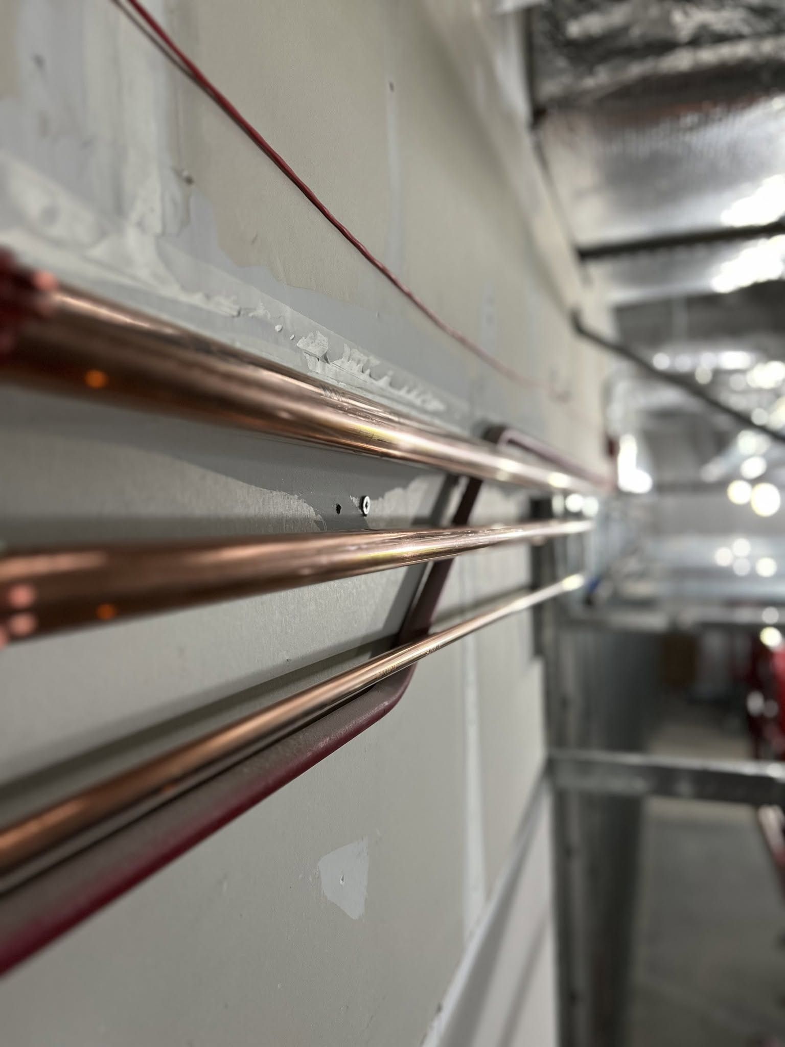 Copper pipes running along a wall in an industrial interior.