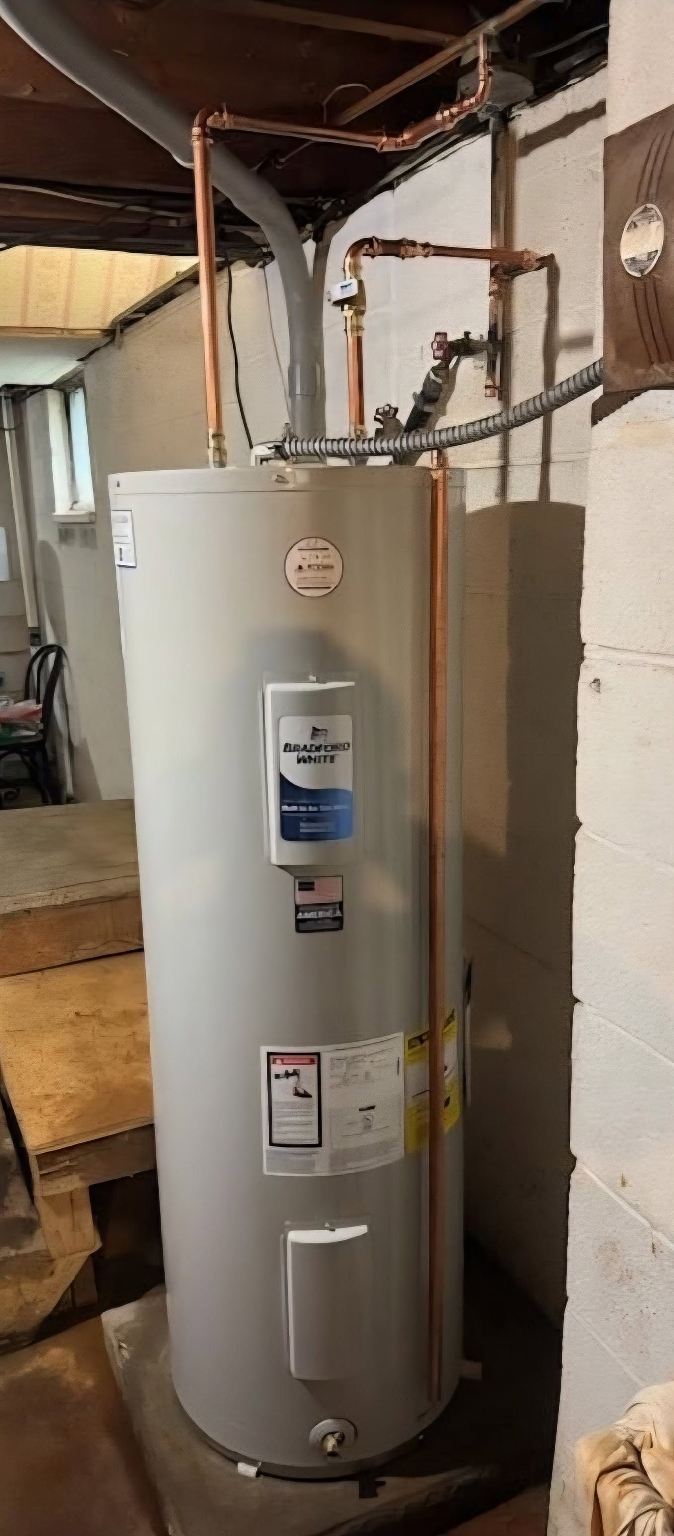 Gas water heater in a basement utility area with exposed pipes and unfinished walls